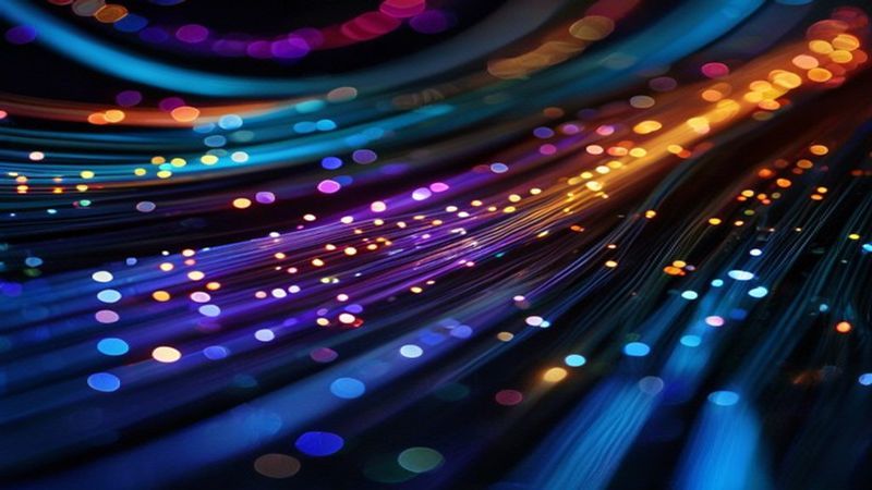 Close-up of fiber optic cables glowing with light streaks in a dark environment, symbolizing data transfer and AI infrastructure